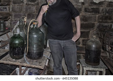 Man In The Private Wine Cellar Next To A Very Large Wine Bottle