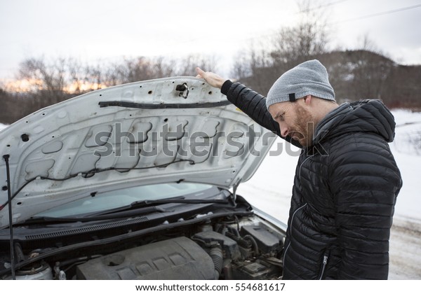 A Man\
problem close to the broken car in\
winter