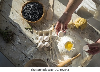 Man In Process Of Making Blueberry Pie. The Ingredients On A Wooden Table. Top View.