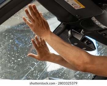 A man in the process of tinting the windshield. The concept of love for cars and protection. Athermal film on the windshield of the car. Car wrapping. Protection of the windshield from sunlight and heat.