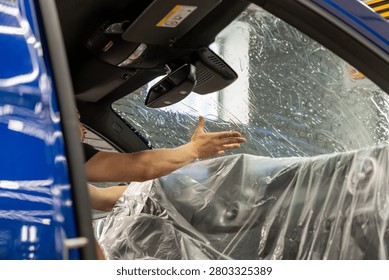 A man in the process of tinting the windshield. The concept of love for cars and protection. Athermal film on the windshield of the car. Car wrapping. Protection of the windshield from sunlight and heat.