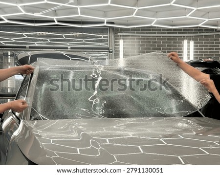 A man in the process of tinting the windshield. The concept of love for cars and protection. The process of installing the PPF on the windshield of a car. Athermal film on the windshield of the car. Car wrapping. Windshield protection. 