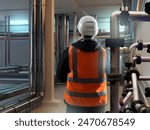 Man in production room. Factory worker with his back to camera. Industrialist stands among pipes. Factory engineer in orange vest. Engineer inspects factory basement. Technologist, contractor