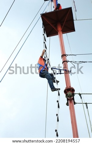 A man propelling on a flying fox at Outward Bound park. Flying fox is a small scale zip line that enable user to propelling by gravity. Outbound
 Stock photo © 