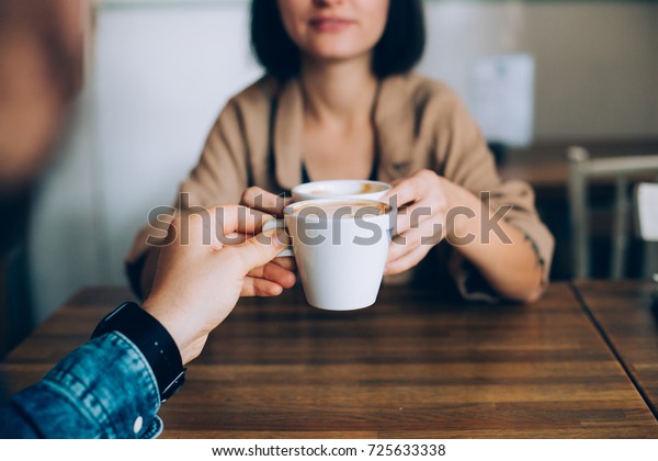 Man\
proposes gives coffee in white little cup to his girlfriend or\
partner, they are in love and are on romantic date in downtown\
stylish cafe or restaurant, drink artisan specialty\

