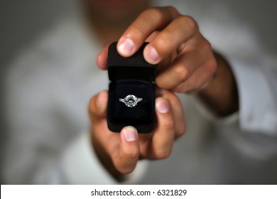 A Man Proposing And Holding Up An Engagement Ring