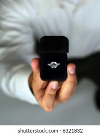 A Man Proposing And Holding Up An Engagement Ring