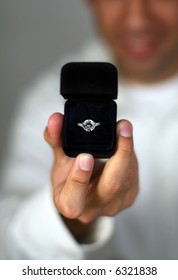 A Man Proposing And Holding Up An Engagement Ring