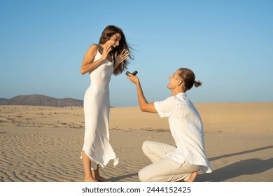 Man proposing to surprised woman on a sandy beach at dusk - Powered by Shutterstock