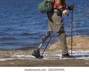 Man with prosthesis of a leg walking by the river. Nordic walk with backpack. Active lifestyle, motivation and tourism concept. - Powered by Shutterstock