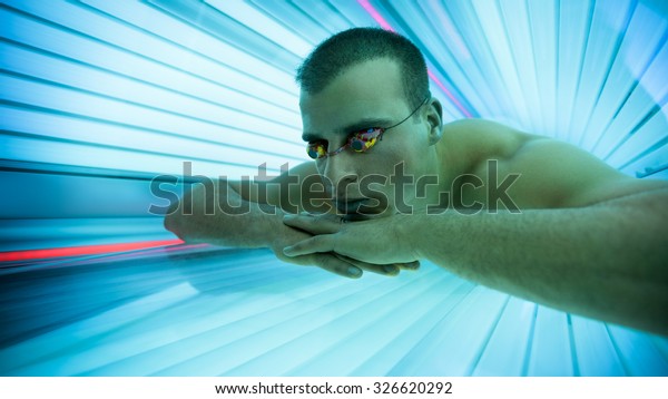 Man with\
protect glasses on tanning bed in\
solarium