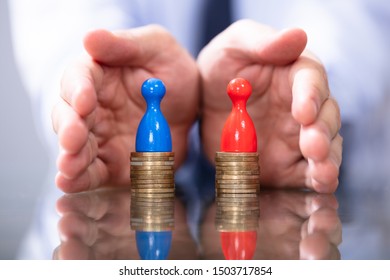 Man Protecting To Coin Stacks. Equal Pay For Men And Women