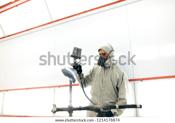 Man with protective clothes and mask painting\
car detail using compressor