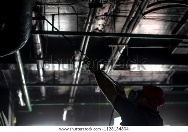 The man in the protective form paints the ceiling\
from the spray gun