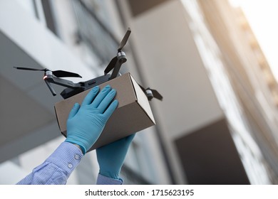 Man In Protective Gloves Receiving Drone With A Delivery Box Package On The Sunset, Copy Space