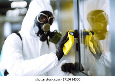  Man In Protective Hazmat Suit Washes Door Handles In Office To Preventing The Spread Of Coronavirus, Pandemic In Quarantine City. Cleaning And Disinfection Of Office. Covid-19.