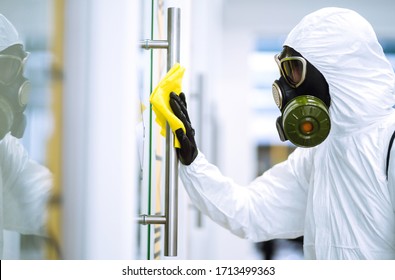 Man In Protective Hazmat Suit Washes Door Handles In Office To Preventing The Spread Of Coronavirus, Pandemic In Quarantine City. Cleaning And Disinfection Of Office. Covid-19.