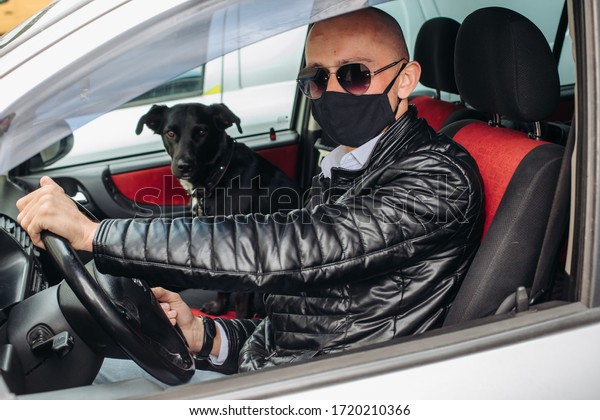 A man in a protective\
mask driving a car. A man in a protective mask driving a car goes\
to the pharmacy.