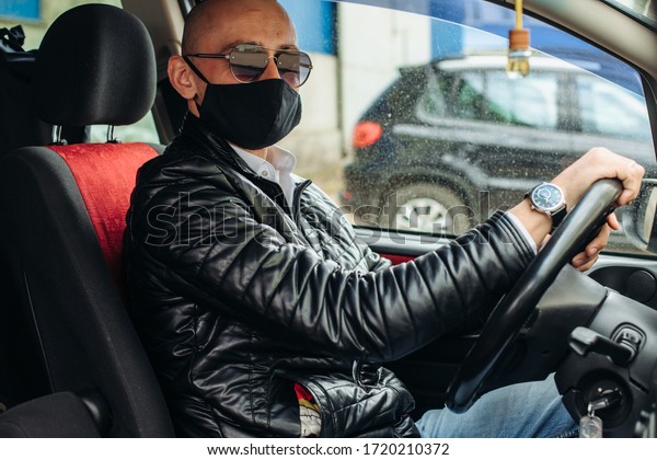 A man in a protective
mask driving a car. A man in a protective mask driving a car goes
to the pharmacy.