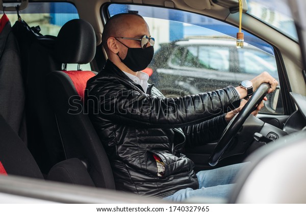 A man in a protective\
mask driving a car. A man in a protective mask driving a car goes\
to the pharmacy.