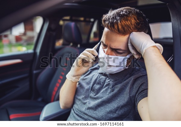 Man with protective mask and\
gloves driving a car talking at mobile phone smartphone. Infection\
prevention and control of epidemic. World pandemic. Stay\
safe.