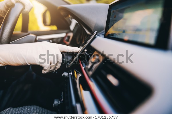 Man with protective mask and\
gloves driving a car typing at mobile phone smartphone. Infection\
prevention and control of epidemic. World pandemic. Stay\
safe.