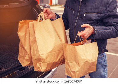 A Man With A Protective Mask On His Face Loads Food Packages Into The Car. Food Delivery. Coronavirus Covid-19