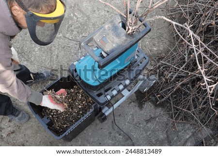 man in a protective mask and work gloves holds a handful of mulch from garden tree branches, processed using a shredder. Conceptually ecology, respect for nature, organic farming.