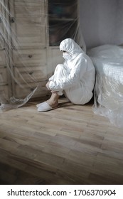 Man In A Protective Medical Suit, Mask And Glasses Seals With Film Furniture, Insanity, Protection From And Repair Dust