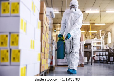 Man In Protective Suit And Mask Disinfecting Warehouse Full Of Food Products From Corona Virus / Covid-19.