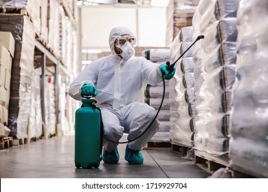 Man In Protective Suit And Mask Disinfecting Warehouse Full Of Food Products From Corona Virus / Covid-19.