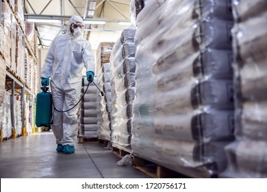 Man In Protective Suit And Mask Disinfecting Warehouse Full Of Food Products From Corona Virus / Covid-19.