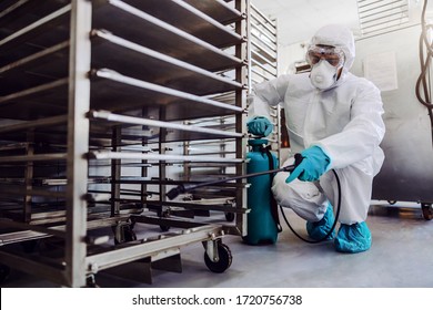 Man in protective suit and mask disinfecting warehouse full of food products from corona virus / covid-19. - Shutterstock ID 1720756738
