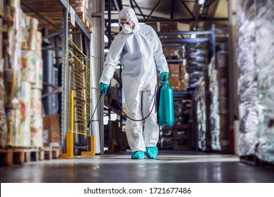 Man In Protective Suit And Mask Disinfecting Warehouse Full Of Food Products From Corona Virus / Covid-19.