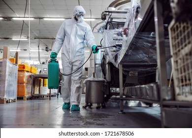 Man In Protective Suit And Mask Disinfecting Warehouse Full Of Food Products From Corona Virus / Covid-19.