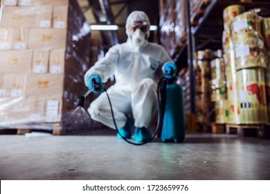 Man In Protective Suit And Mask Disinfecting Warehouse Full Of Food Products From Corona Virus / Covid-19.