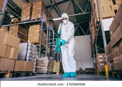 Man in protective suit and mask disinfecting warehouse full of food products from corona virus / covid-19. - Shutterstock ID 1765684568