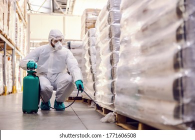 Man In Protective Suit And Mask Disinfecting Warehouse Full Of Food Products From Corona Virus / Covid-19.