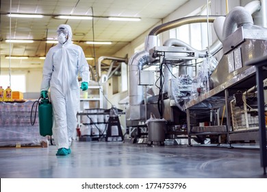 Man In Protective Suit And Mask Disinfecting Food Factory Full Of Food Products From Corona Virus / Covid-19.