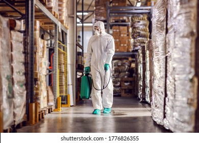 Man In Protective Suit And Mask Disinfecting Warehouse Full Of Food Products From Corona Virus / Covid-19.