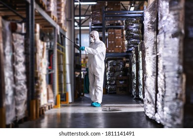 Man in protective suit and mask disinfecting warehouse full of food products from corona virus / covid-19. - Shutterstock ID 1811141491