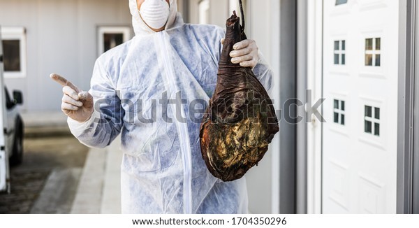 Man with protective suit and mask holding\
bad meat ham, rotten meat. Infection prevention and control of\
epidemic. World pandemic.  World pandemic\
