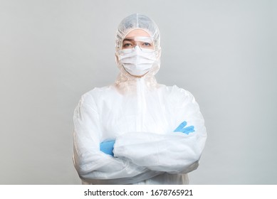 Man in protective suit, medical mask, goggles with arms crossed. Isolated in studio
