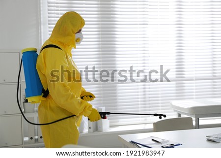 Man in protective suit sanitizing doctor's office. Medical disinfection
