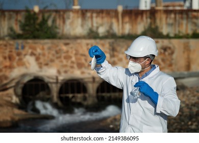 A Man In A Protective Suit Takes A Sample Of Water From The River After The Release Of Chemical Waste