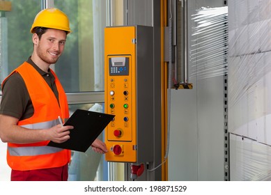 Man in protective vest and hardhat operating a wrapping machine
