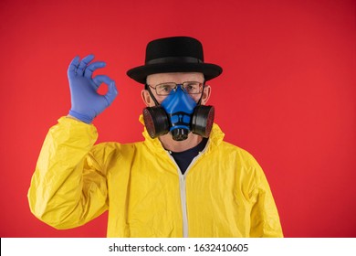 A man in a protective yellow suit and chemical mask, glasses and a black hat shows the sign OK. The image of Walter White, Heisenberg. Concept Breaking Bad. Underground Chemist.