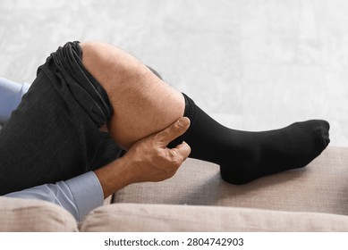 Man pulling up black sock on leg while sitting