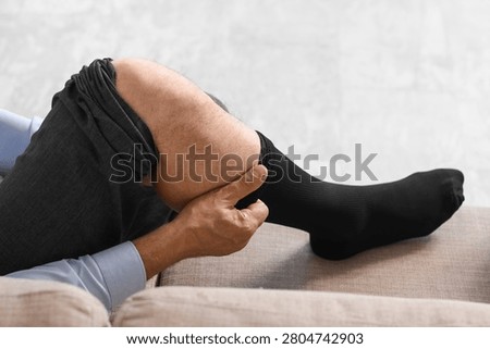 Man pulling up black sock on leg while sitting
