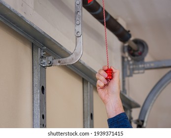 Man Pulling Manual Safety Release Cord Handle Before Performing Maintenance On Electric Garage Door Opener.